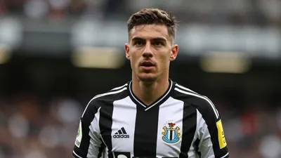 A young, athletic Newcastle United left-back, 20s, with determined expression, fills the frame, wearing the black and...