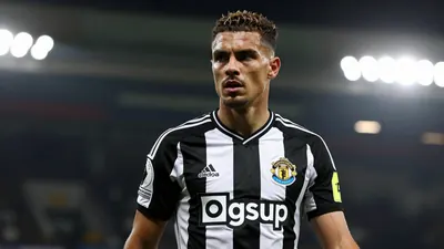 A 30-year-old Newcastle United player with a strong build, wearing a black and white kit, photographed with an 85mm f/1.4...