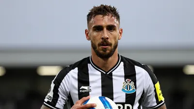 Mid-30s, athletic midfielder, slightly scruffy beard, intense gaze, black-and-white striped home shirt of Newcastle...