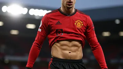 A tight action crop of an anonymous Newcastle United player in a red and black kit, with the player's face visible and...