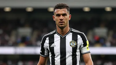 Mid-30s muscular Newcastle United forward, waist-up, intense gaze toward camera, black and white home jersey with crisp...