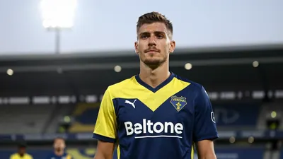 A 25-year-old right-back in a Hellas Verona kit, with a confident expression, standing in front of a stadium, with a...