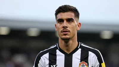 Mid-20s athletic midfielder, intense gaze, head-and-shoulders, wearing Newcastle United black-and-white home shirt with...