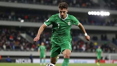 Photorealistic image of a 24-year-old athletic winger in a solid green kit, mid-sprint with the ball at his feet, blurred...