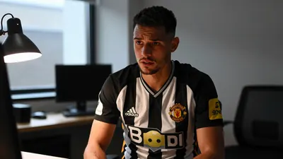 A tight waist-up shot of a Newcastle United player in a black and white jersey with a white collar, looking concerned as...