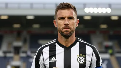 A photorealistic image of an anonymous 35-year-old male coach with a rugged build, wearing a black and white striped...