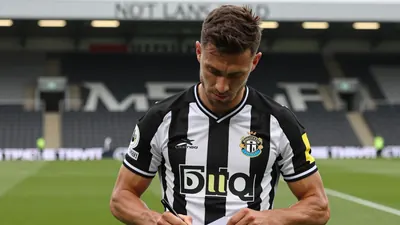 A muscular, mid-20s defender in Newcastle United's black-and-white home kit, the club crest sharply rendered on his left...