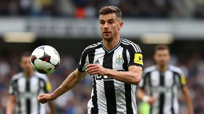 A tight waist-up shot of an anonymous Newcastle United midfielder, wearing a black and white jersey with a smooth...