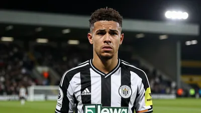 A young Newcastle United midfielder in a black and white striped shirt, waist-up, frustrated expression after a missed...
