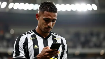 A tight shot of a 28-year-old Brazilian midfielder in a black and white striped jersey, head slightly tilted, looking...