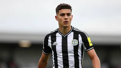 Young 21-year-old left-back, athletic build, waist-up, intense expression, short dark hair, clean-shaven, eyes focused...