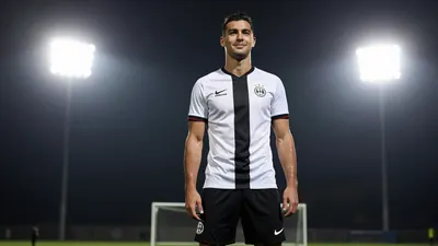A tight waist-up shot of an anonymous 28-year-old male player in a white jersey with a black stripe, black shorts, and...