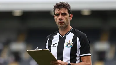 Middle-aged, lean male coach, mid-40s, short dark hair, intense expression, waist-up portrait, wearing Newcastle United...